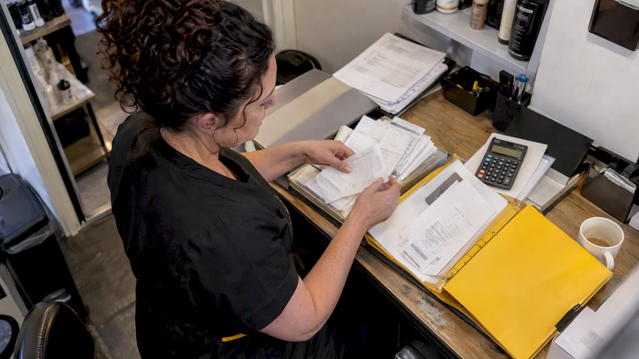 Salon owner sorting receipts and card payment slips at the front desk