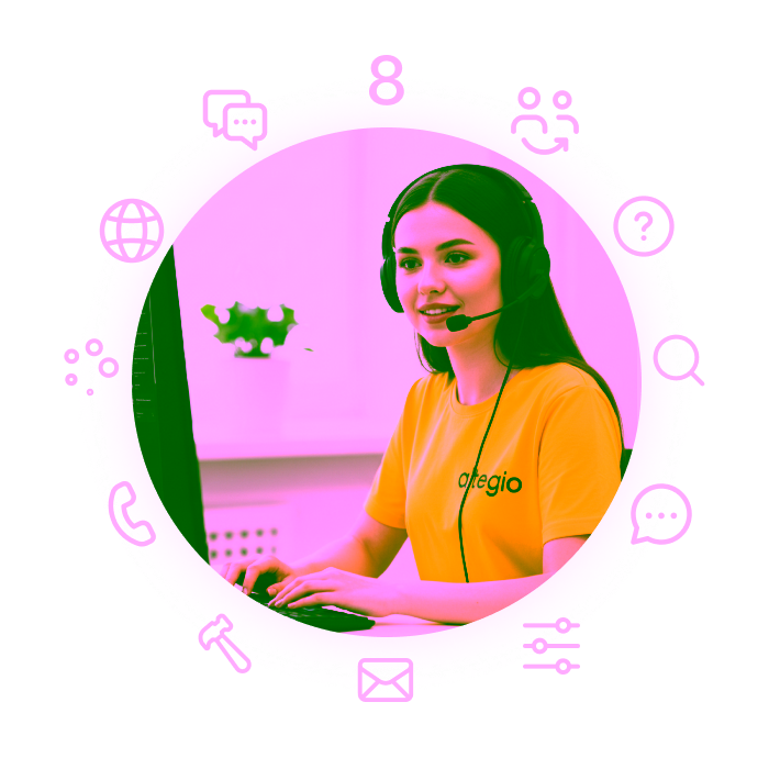 Молода жінка в жовтій сорочці та гарнітурі працює за комп'ютером у світлому офісі.