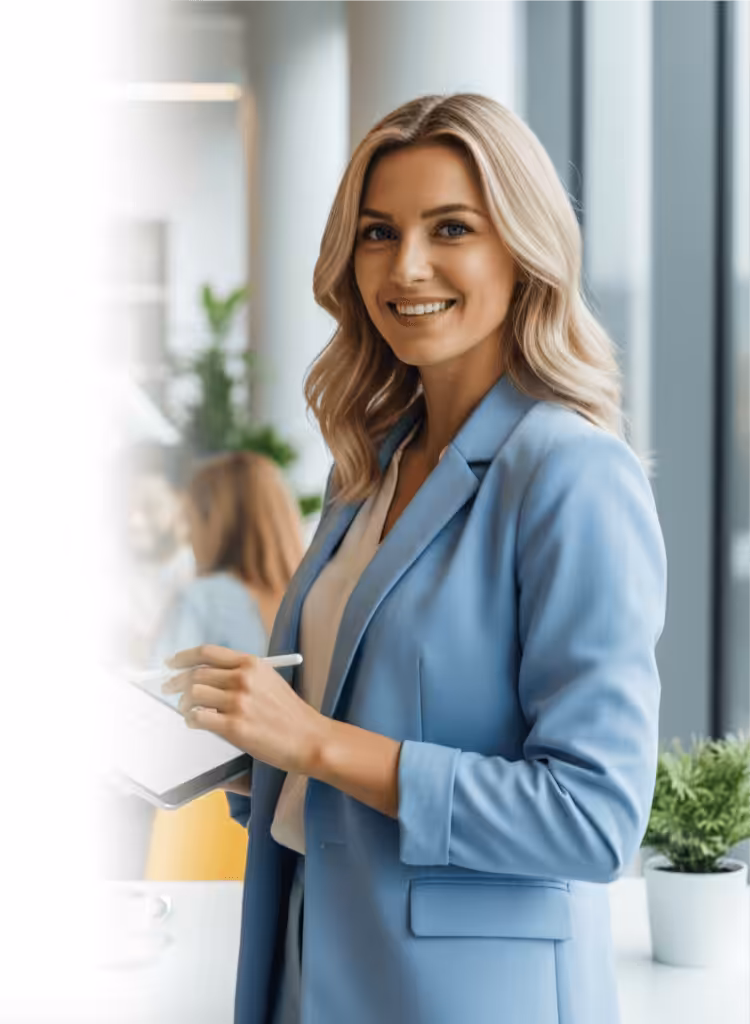 A professional woman in a blue suit holding a tablet and smiling in a modern office setting.